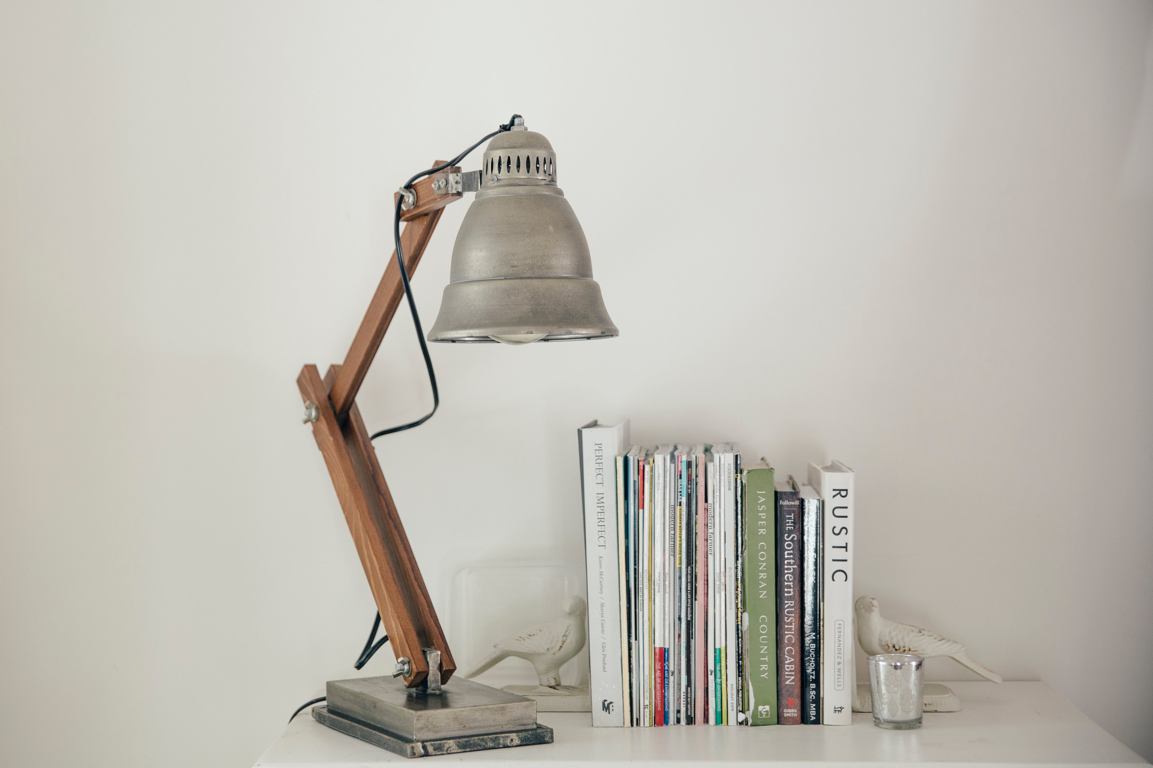 Books on a table next to a grey table lamp.